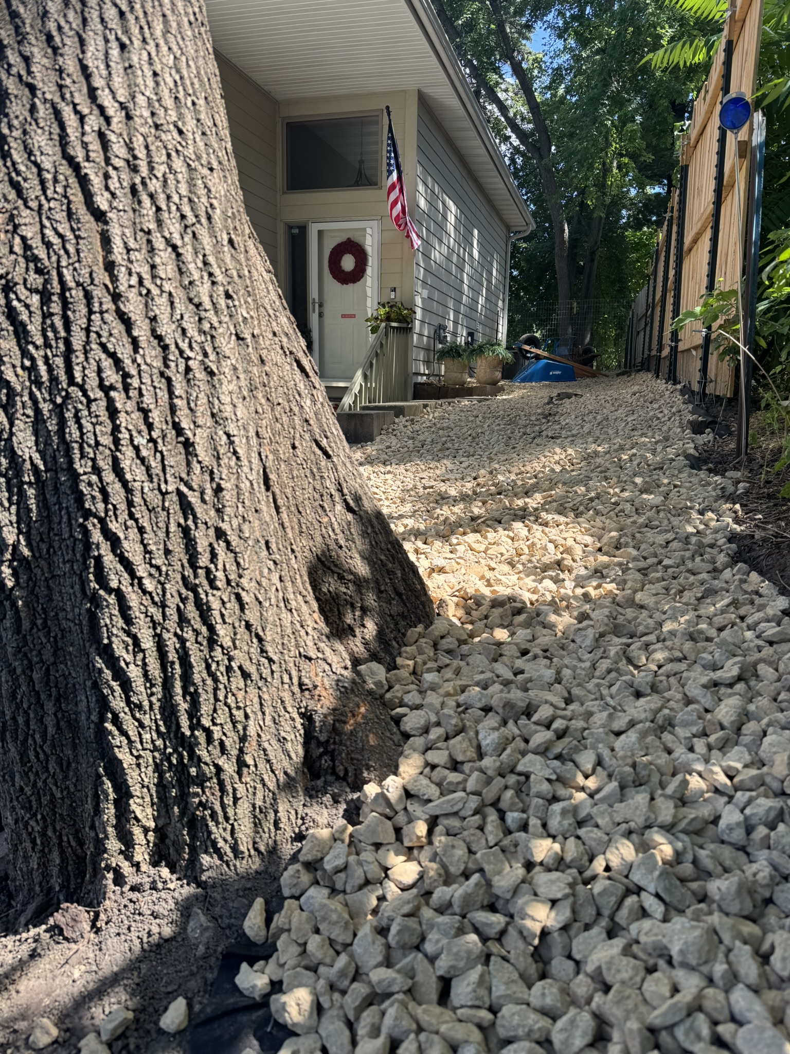 Finished side yard filled with decorative rock running from a mature tree to the front steps in Mound Minnesota