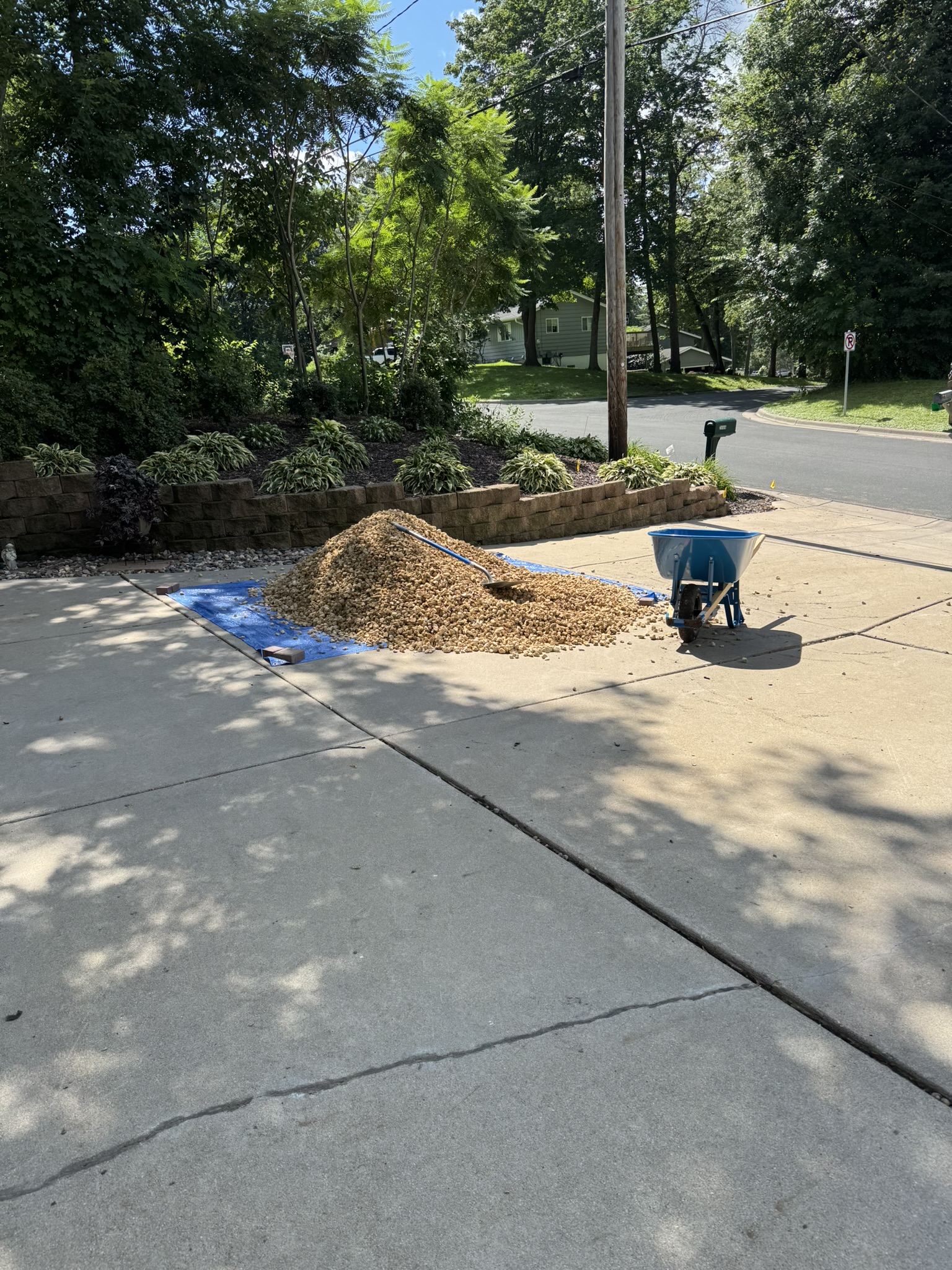Pile of decorative landscaping rock staged on a tarp in a residential driveway in Mound Minnesota