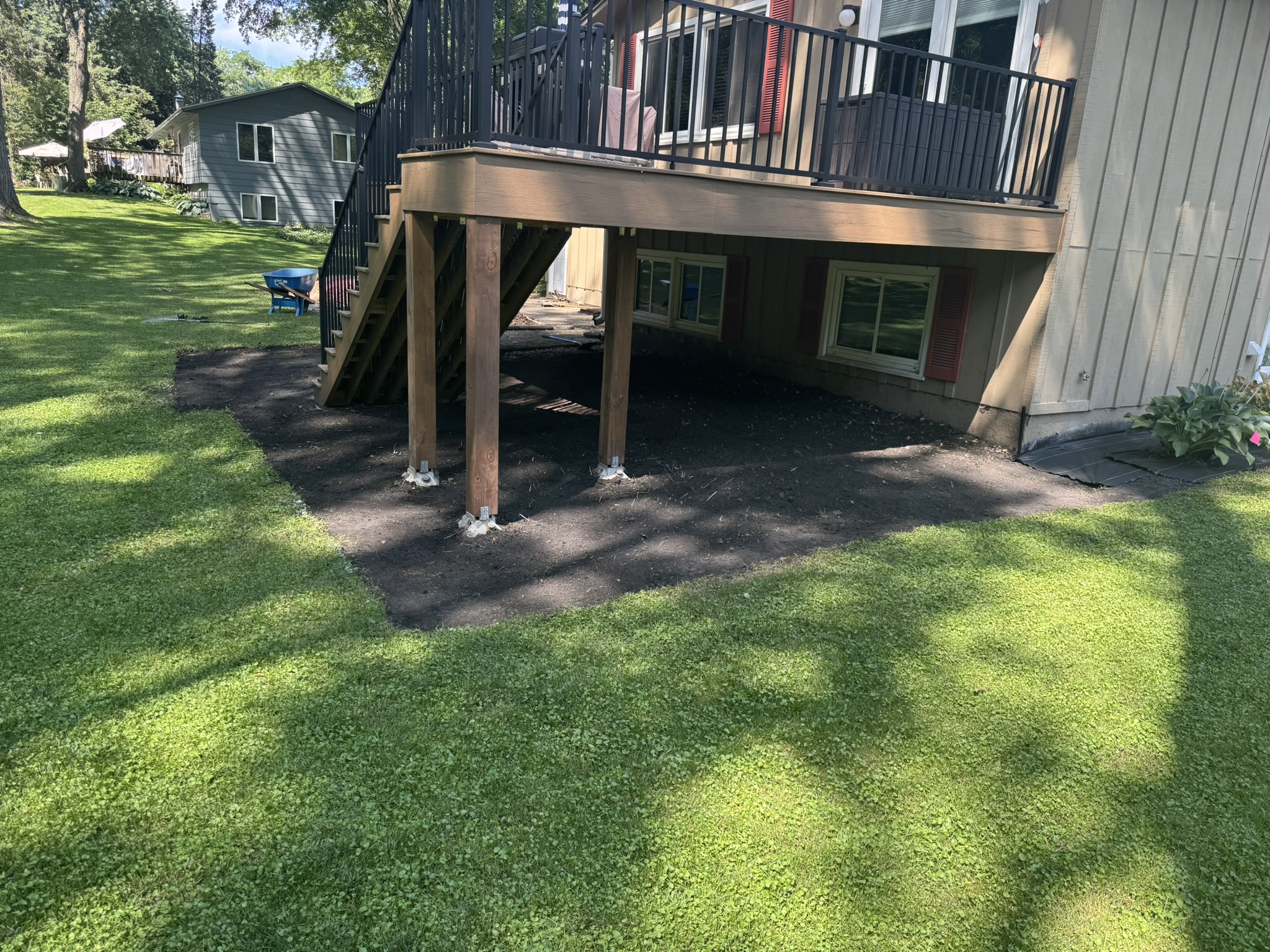 Backyard area under a deck dug out to bare soil before fabric and edging in Minnetonka Minnesota
